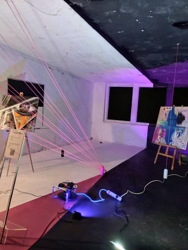 Moderne Kunstausstellung mit neonfarbenen Linien und Malutensilien auf dem Boden.